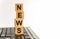 Concept image a wooden block and word News on white background. The cubes are located on the keyboard. Selective focus.