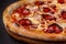 The concept of Italian cuisine. Real Italian pizza on a thin cake with large sides on a black background. Close up. Background