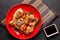 The concept of Japanese and Chinese cuisine. Chicken fried legs with hot pepper, sesame, chuka salad, Chinese peas on black table