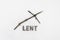 Concept for Lent Season. Wooden Cross or crucifix and text made of ashes on snow background