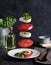 Concept levitation food. Italian caprese salad with tomatoes, mozzarella cheese, basil and pesto sauce flies over the plate on a