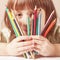 Concept: life is beautiful and colorful. Humorous photo of great artist. Portrait of cute little child girl with colored pencils