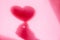 Concept modern abstract background of shadow heart in hand on a pink wall