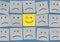 Concept of mood expression with an emoticon with an optimistic smile, in the middle of another pessimist.