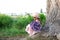 The concept of nature and romance. Happy childhood. A little cute girl in a straw hat sits on a tree with a huge bouquet of wildfl