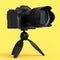 Concept of nonexistent DSLR camera with tripod isolated on yellow monochrome