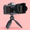 Concept of nonexistent silver DSLR camera with tripod isolated on pink.