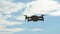 Concept of personal drones and aerial photography. Quadcopter flying overhead in cloudy blue sky