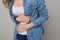 Concept of pms. Sad unhappy woman is having symptoms of pms, she is touching her stomach. Isolated on grey background, cropped pho