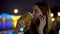 Concept portrait of busy lady communicating via smartphone drinks coffee on the night blurred urban background of the