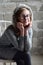 Concept portrait of a pleasant friendly happy teenager in glasses on chair. Young girl is sitting in a gray dress and smiling