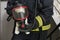 The concept of protecting children alone at home: a firefighter holds a teddy bear in a breathing mask in smoky rooms