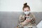 Concept quarantine, self-isolation. The girl is sick, sits at home in a mask, wrapped herself in a checkered blanket and holds a p