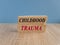 Concept red words Childhood trauma on brick blocks. Beautiful wooden table, blue background. Business psychology childhood trauma