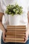 The concept of relocation and moving to a new home. Close-up, female hands hold a pile of books and a green plant in a