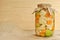 Concept of seasonal pickles jar covered with sackcloth full of colored green raw tomatoes, orange carrot and white cauliflower on