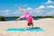 The concept of sport and active play in the summer. Girl doing gymnastics while relaxing on the beach
