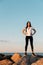 The concept of sport and a healthy lifestyle. A young woman in sportswear , standing on the coastal rocks, hands on hips. Copy