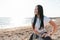 The concept of sport. A young brunette is engaged in a warm-up, squatting on the beach. At the back of the sea and the horizon