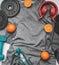 Concept of sports lifestyle, headphones, dumbbells, oranges, a bottle of water, a t-shirt for training place for text flat lay