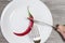 Concept of strict dieting. Close up photo of woman`s hands cutting chili pepper on a plate heartburn burn eating nutrition weight