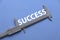 Concept of success. Top view of opening calipers measuring a word SUCCESS on a blue background