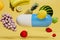 the concept of taking a vitamin complex. a medical capsule around which fruits on a yellow background. 3D render