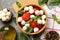 Concept of tasty eating with bowl of mozzarella, tomato and basil on gray table