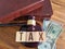 Concept of tax law and word tax with hammer and money on table