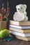 Concept of Teacher\'s Day. Objects on a chalkboard background. Books, green apple, bear with a sign: Happy Teacher\'s Day, pencils