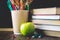 Concept of Teacher\'s Day. Objects on a chalkboard background. Books, green apple, pencils and pens in a glass, twig with autumn l