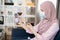 Concept of telemedicine and patient consulting online. Sick Muslim woman feeling bad at home, measuring body temperature