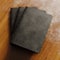 Concept of three blank notebook with black textured paper cover on wooden desk.Closeup empty horizontal mockup.Top view