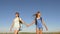 Concept tourism and travel. girls, women travelers go holding hands on a background of blue sky. teamwork tourists