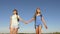 Concept tourism and travel. girls, women travelers go holding hands on a background of blue sky. teamwork tourists