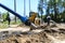 Concept of the tractor, the tractor digs and buries a trench for laying water on a forest plot for the construction of the house.