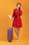 Concept of travel. happy woman girl with suitcase, camera and passport on orange colored background