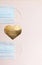 The concept of valentine`s day during a pandemic. Medical protective masks and a heart shape of gold color