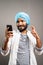 concept of wating for job promotion, lottery or interview results showing by tensed Young sikh man using mobile phone on