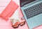 The concept of web work at a beach resort, freelancing. Laptop, flash drive, sunglasses, shell, purse on a pink color wooden table