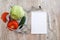 The concept of weight loss and healthy eating. Vegetables in a plate, measuring tape and notebook with pen on a wooden century. Vi