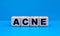 Concept word ACNE on cubes on a blue background