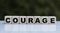 The concept of the word COURAGE on cubes on a beautiful green background