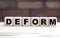 Concept word DEFORM on cubes against the background of a brick wall