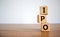 Concept word `IPO` - `initial public offering` on wooden cubes on a beautiful woodet table, white background. Business concept