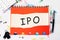 The concept of the word IPO, written on a piece of paper lying on a notebook on the table