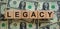 Concept word `legacy` on wooden cubes on a beautiful background from dollar bills. Business concept