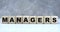 Concept word managers on wooden cubes on a gray background