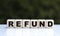 The concept of the word REFUND on cubes on a beautiful green background