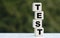 The concept of the word TEST on cubes on a beautiful green background